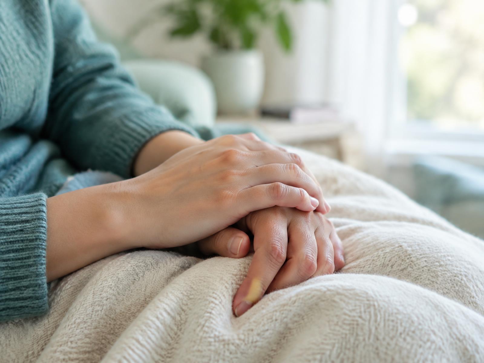 Two hands resting gently on a blanket